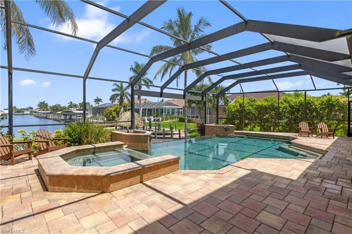 View of swimming pool with an in ground hot tub, a water view, a patio area, and a lanai