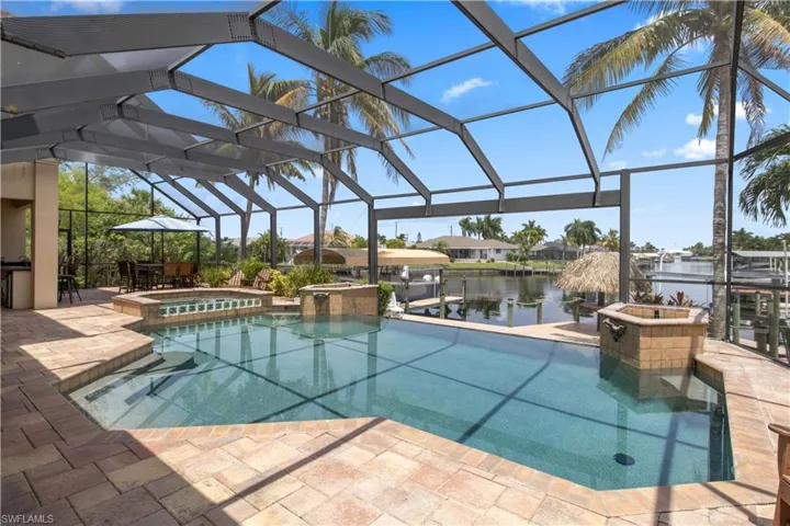 View of swimming pool featuring an in ground hot tub,  a covered patio, and a water view