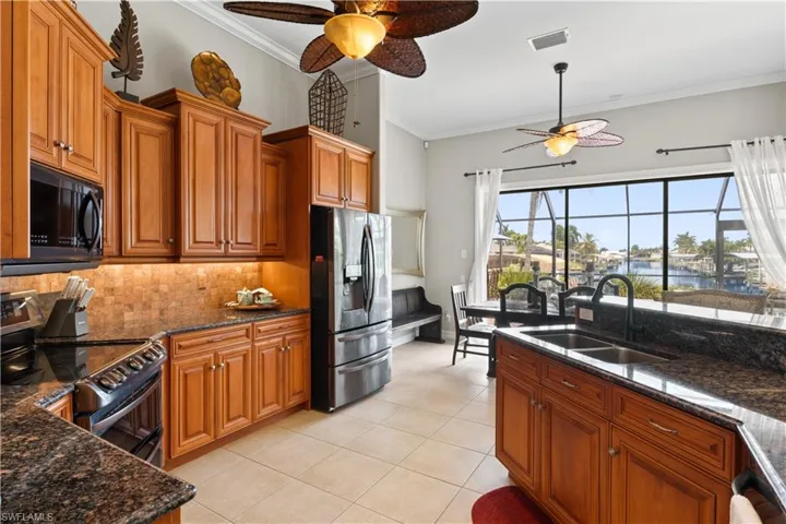 Kitchen featuring ceiling fan, backsplash, electric range oven, sink, and stainless steel fridge with ice dispenser