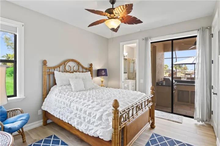 Guest bedroom featuring ceiling fan, light hardwood / wood-style flooring, ensuite bathroom, and multiple windows