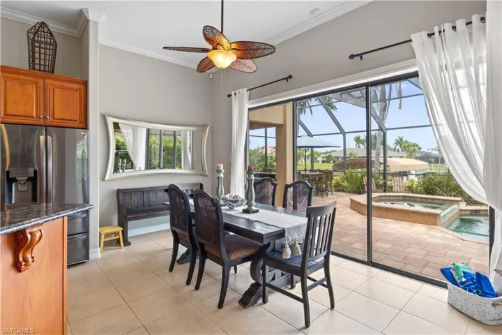 Dining room with ceiling fan, crown molding, and light tile patterned flooring
