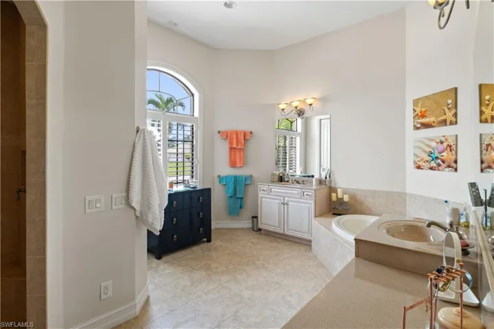 Master bathroom featuring tile patterned floors, plenty of natural light, vanity, and tiled bath