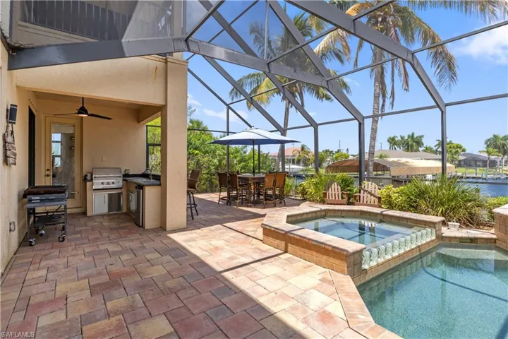 View of pool featuring an in ground hot tub, a lanai, a patio area, ceiling fan, and a grill