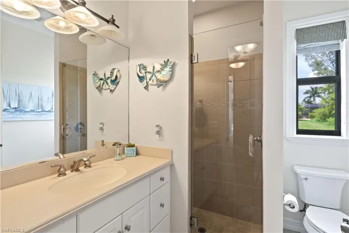 Guest bathroom with an enclosed shower, toilet, a healthy amount of sunlight, and vanity