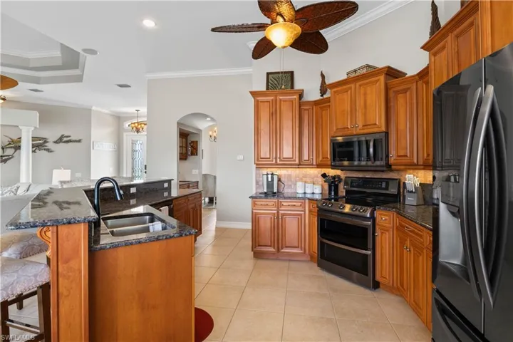 Kitchen featuring appliances with stainless steel finishes, tasteful backsplash, sink, crown molding, and a breakfast bar area