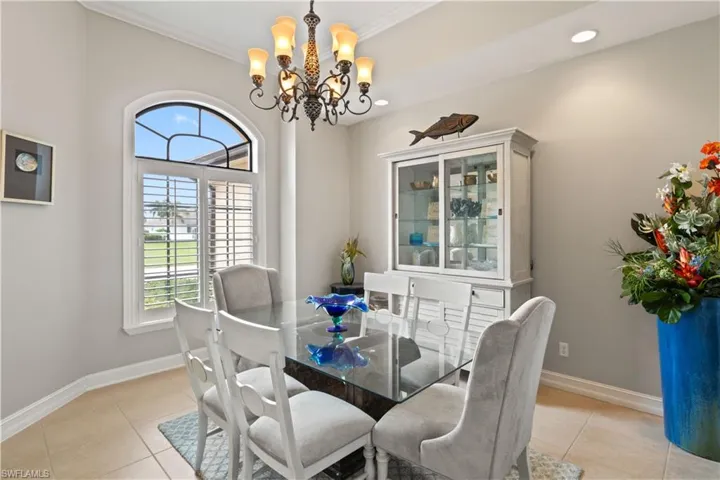 Tiled dining area with an inviting chandelier and ornamental molding
