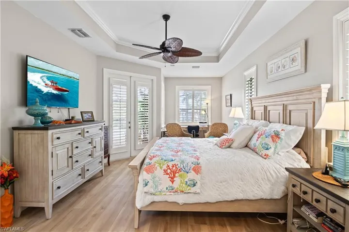 Master bedroom with light hardwood / wood-style floors, crown molding, a raised ceiling, access to exterior, and ceiling fan