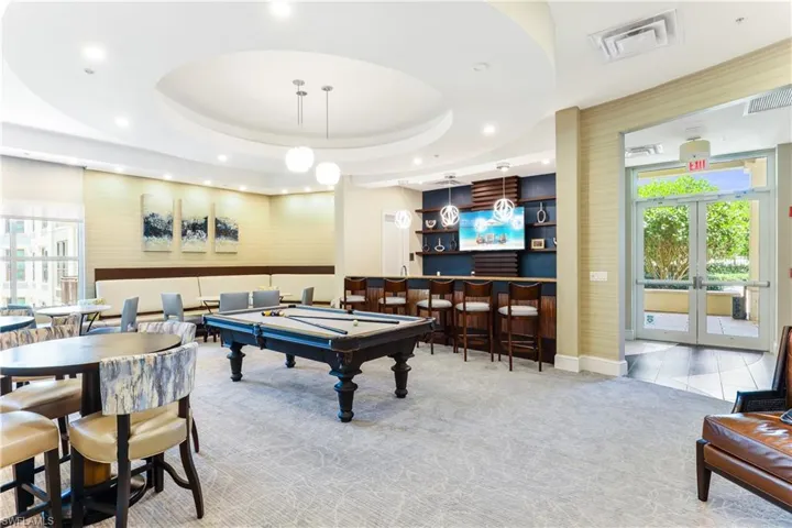 Game room featuring pool table, french doors, light colored carpet, a tray ceiling, and bar