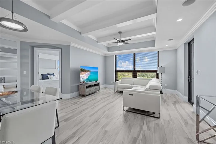 Living room with ceiling fan, light hardwood / wood-style floors, and ornamental molding