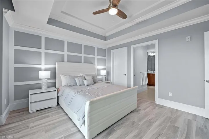 Bedroom with ensuite bath, crown molding, light hardwood / wood-style flooring, and ceiling fan
