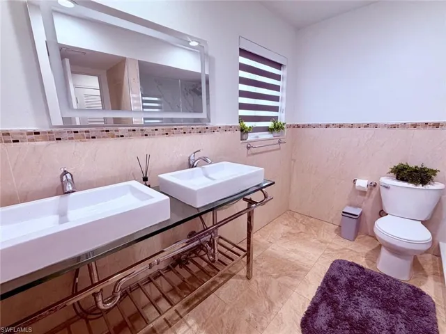 Full bathroom featuring a wainscoted wall and tile walls