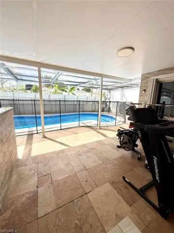 View of pool featuring a sunroom, patio surround, glass enclosure, and a fenced backyard