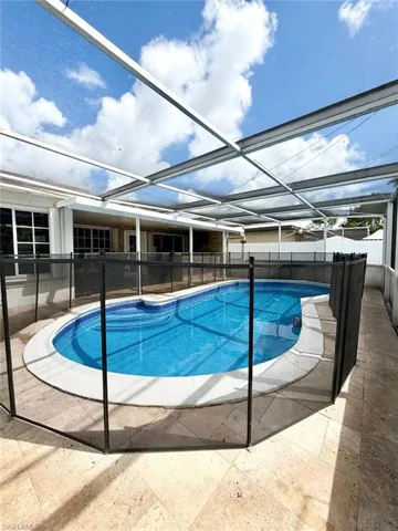View of pool with a fenced backyard, patio surround, glass enclosure, and a sunroom