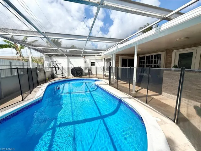 View of swimming pool featuring a sunroom, a lanai, a fenced backyard, patio surround, and area for grilling