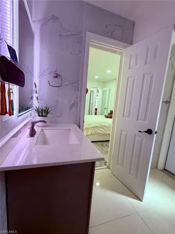 Bathroom with vanity, ensuite bathroom, and tile walls