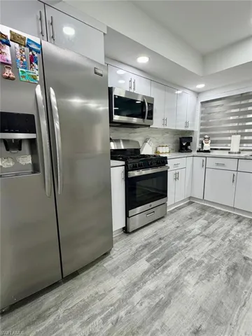 Kitchen featuring stainless steel appliances, white cabinets, recessed lighting, light wood-style floors, and backsplash