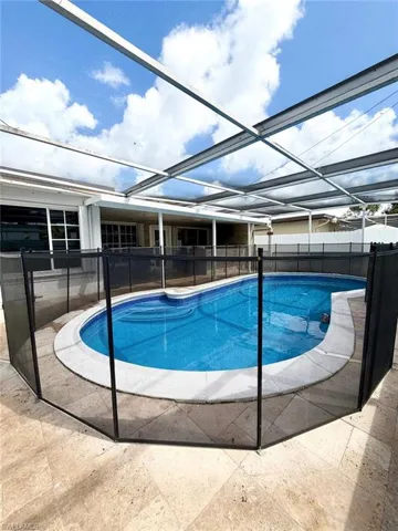 View of pool with a fenced backyard, glass enclosure, patio surround, and a sunroom