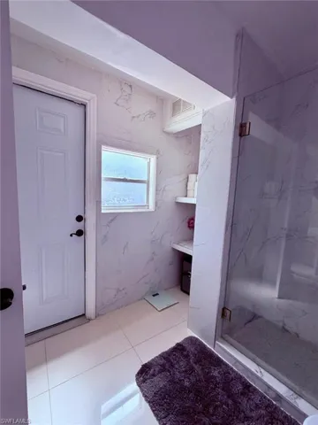 Full bath with a marble finish shower and light tile patterned floors