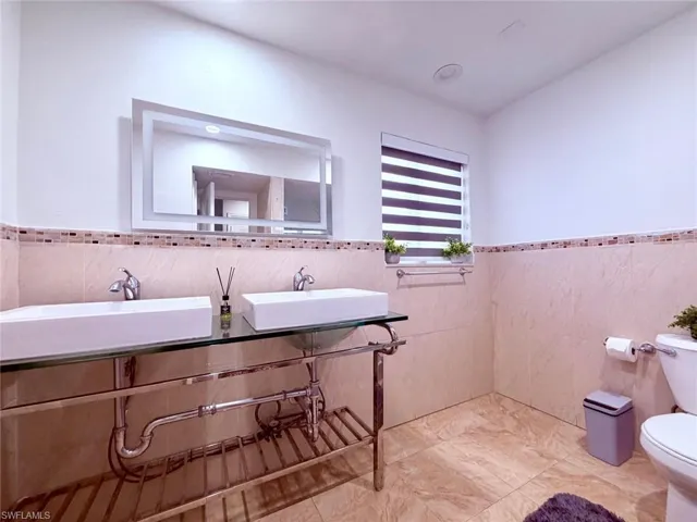 Bathroom with a wainscoted wall and tile walls