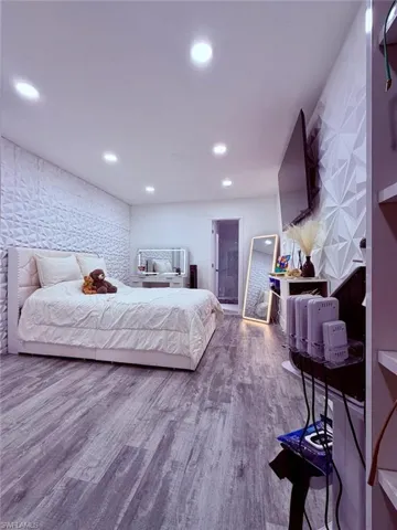 Bedroom featuring light wood-style floors, recessed lighting, and an accent wall