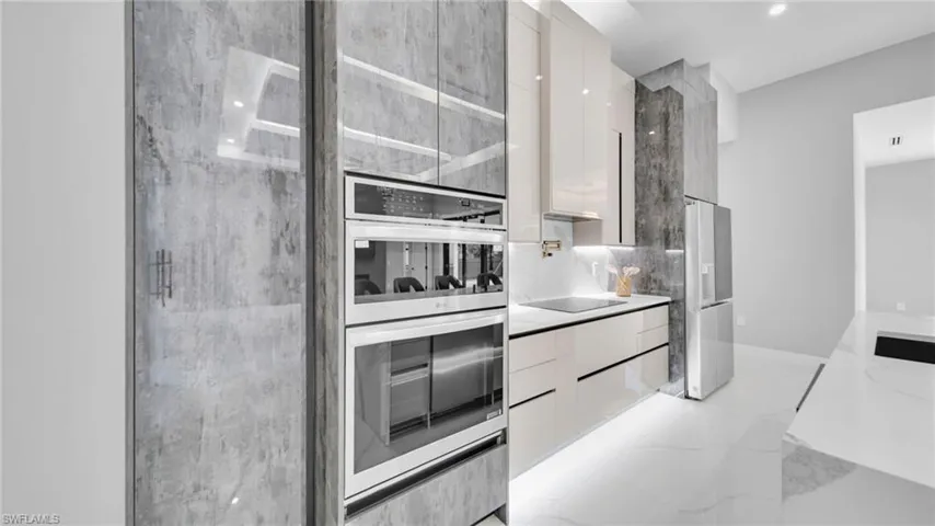Kitchen featuring modern cabinets, white cabinetry, and appliances with stainless steel finishes