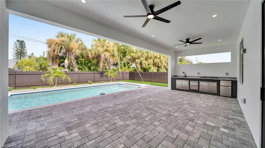 View of swimming pool with a fenced backyard, an outdoor kitchen, a patio area, and a ceiling fan