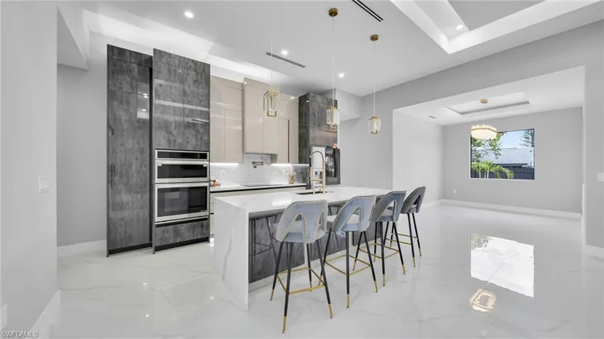 Kitchen with modern cabinets, light marble finish floors, decorative light fixtures, and recessed lighting
