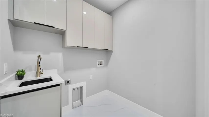 Washroom featuring cabinet space, hookup for a washing machine, hookup for an electric dryer, and light marble finish floors