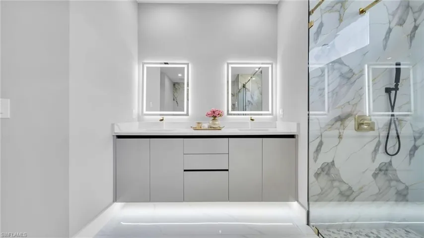 Full bathroom with double vanity and a marble finish shower