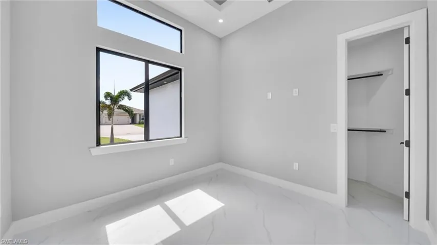 Unfurnished bedroom with light marble finish flooring, recessed lighting, and a spacious closet