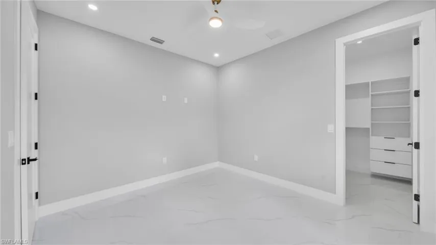 Unfurnished bedroom with light marble finish flooring, a spacious closet, recessed lighting, and ceiling fan