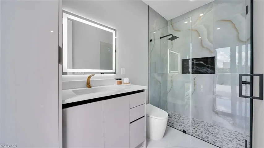 Bathroom featuring a marble finish shower, vanity, and recessed lighting