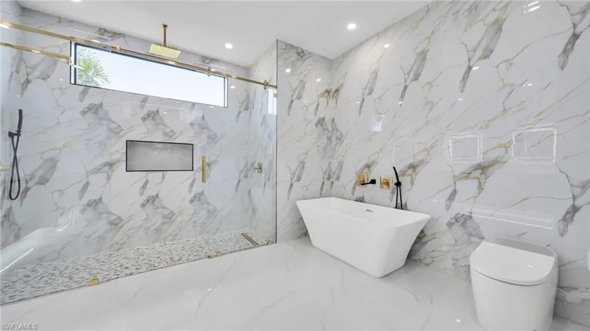 Bathroom with stone wall, a soaking tub, a marble finish shower, recessed lighting, and tile walls