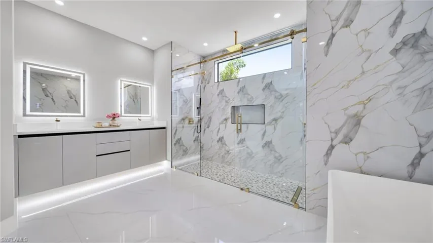 Full bathroom with a soaking tub, a marble finish shower, stone wall, double vanity, and recessed lighting