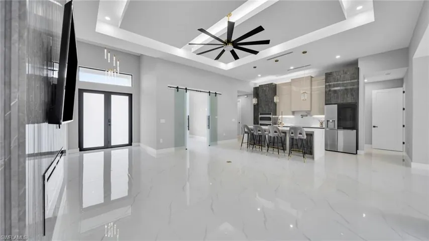 Kitchen with modern cabinets, a raised ceiling, open floor plan, a barn door, and stainless steel refrigerator with ice dispenser