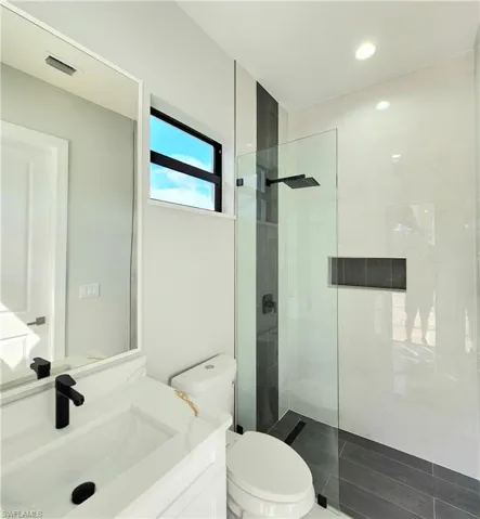 Bathroom featuring toilet, visible vents, a walk in shower, and vanity