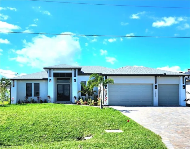 Prairie-style house featuring a front yard, decorative driveway, an attached garage, and stucco siding