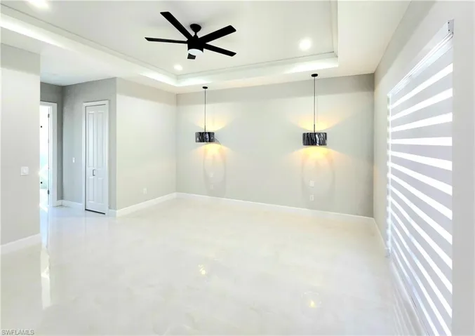 Empty room with ceiling fan, recessed lighting, a raised ceiling, and baseboards
