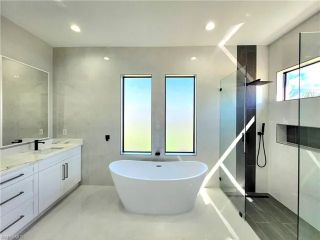 Full bathroom featuring a walk in shower, vanity, tile walls, marble finish floor, and a soaking tub