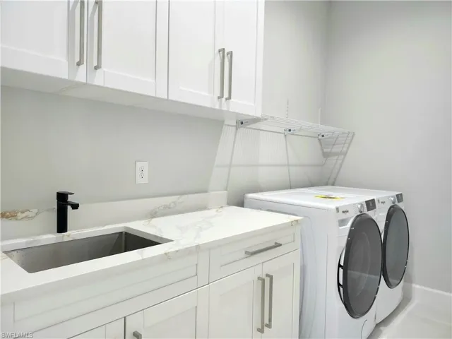 Washroom featuring cabinet space, a sink, and separate washer and dryer