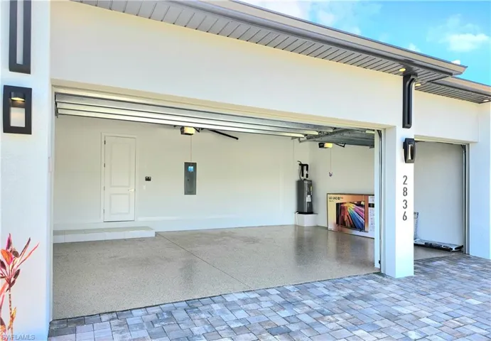 Garage with water heater, ceiling fan, and decorative driveway