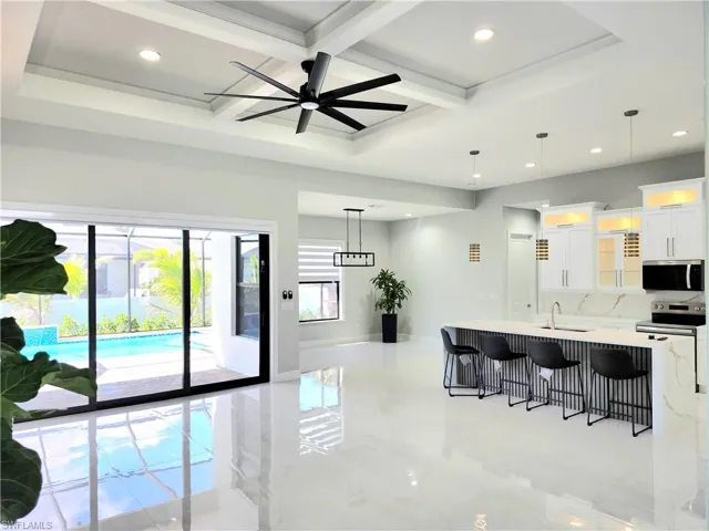 Kitchen with stainless steel appliances, a breakfast bar, white cabinetry, light countertops, and glass insert cabinets