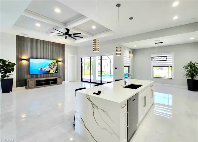 Kitchen featuring light stone counters, a kitchen island with sink, a sink, white cabinets, and dishwasher