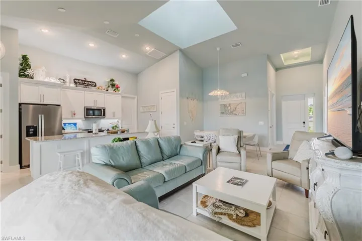 Open-concept living space featuring vaulted ceilings, two skylights, recessed lighting, and tile flooring