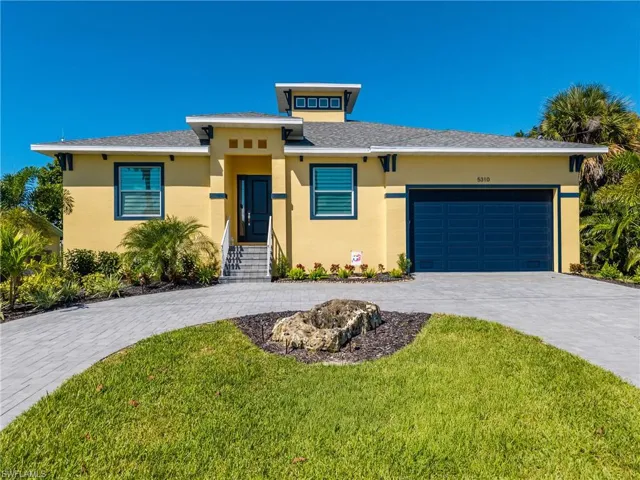 Contemporary residence featuring a yellow exterior with dark trim accents and a contrasting dark garage door