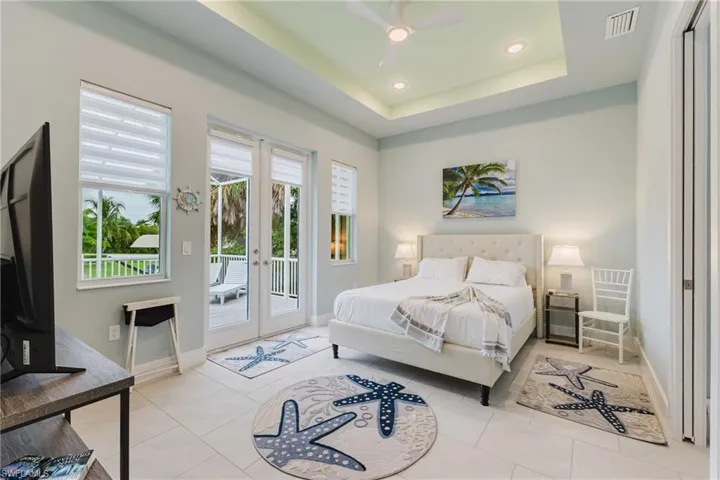 Recessed lighting, a tray ceiling, and a ceiling fan illuminate this space featuring light tile flooring