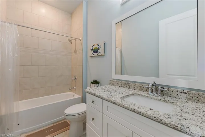 Bathroom featuring a white vanity with a light-toned granite countertop, an undermount sink, and chrome fixtures