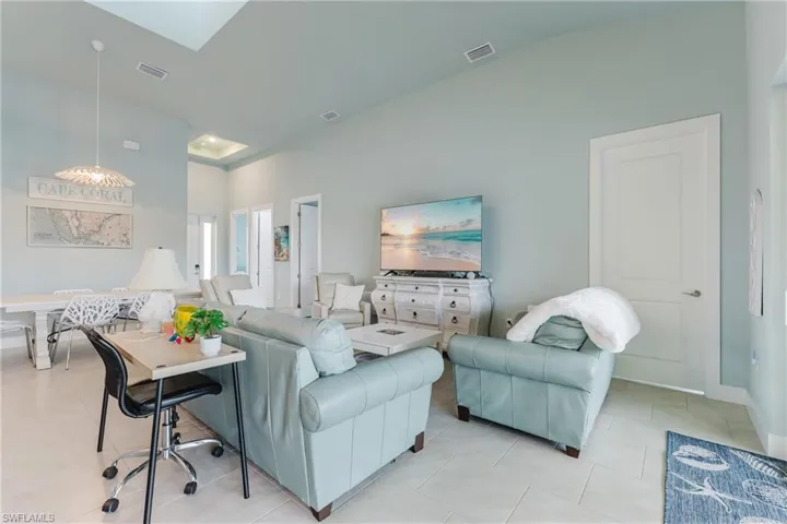 Open-concept living area featuring vaulted ceilings, recessed lighting, and light-toned tile flooring