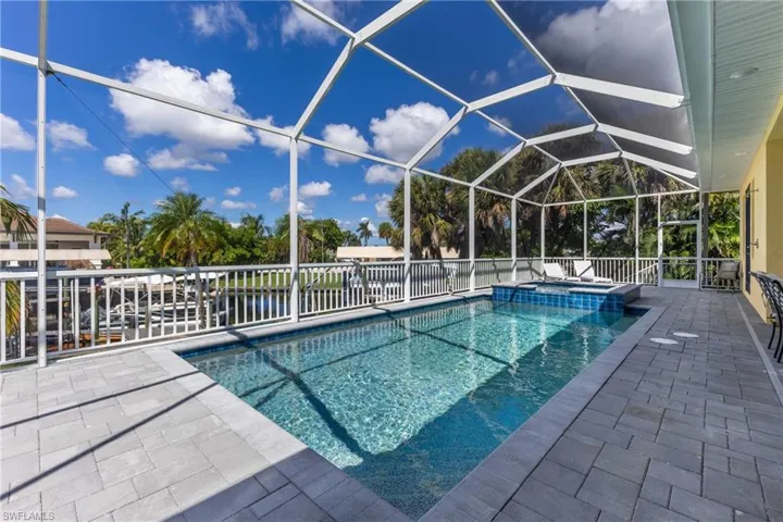 Screened pool enclosure featuring a rectangular pool, integrated spa, and paver decking