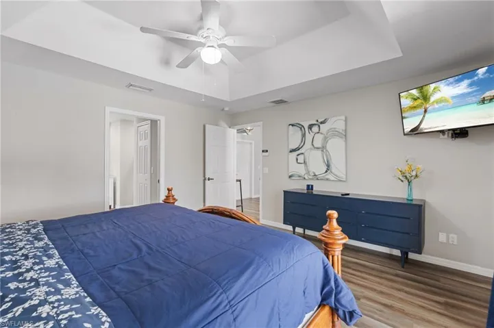 Bedroom featuring baseboards, visible vents, wood finished floors, and a raised ceiling